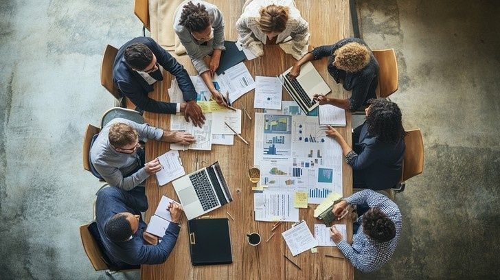 Grupp diskuterar diagram och affärsdokument runt ett mötesbord