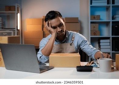 Trött företagare vid skrivbord med laptop, kartong och kaffemugg
